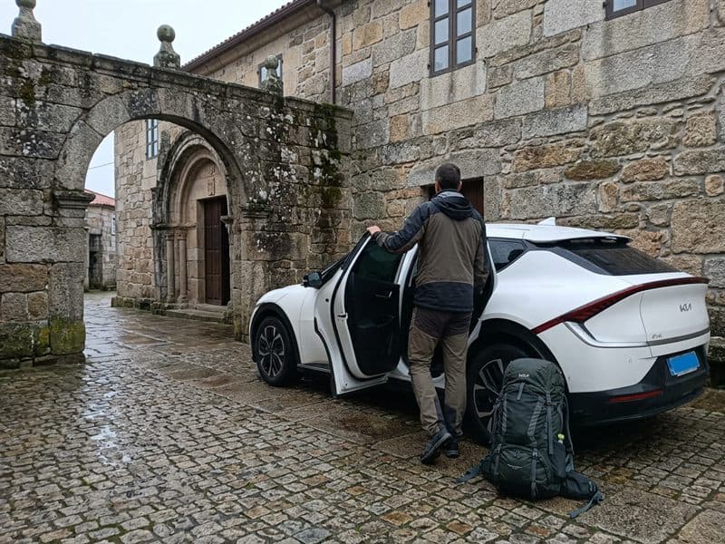 Peregrino subiendo al taxi de Taxi Ribeira Sacra frente a un albergue de piedra en Lugo