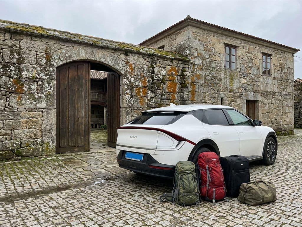 Equipaje de peregrinos preparado junto al taxi de Taxi Ribeira Sacra ante una casa de piedra